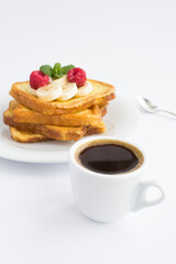 French toasts with banana, raspberry and coffee cup on the white background. Breakfast. Location vertical.