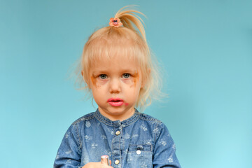 A portrait of a child who put on parental makeup on his own. Small children and high fashion.