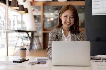A businesswoman is checking company financial documents and using a laptop to talk to the chief...