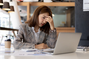 A businesswoman has a headache after working in front of her laptop for a long time and looking at...