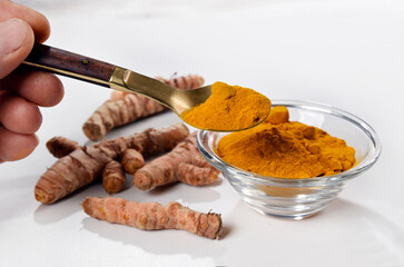 Turmeric powder with turmeric roots in the background