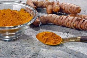 Turmeric powder with turmeric roots in the background