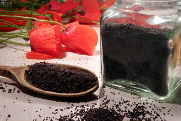 poppy seeds in a spoon, with poppies nearby