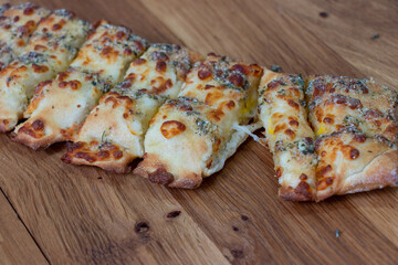 Oven baked garlic bread. Sliced cheese garlic bread with white sauce on a wooden background....