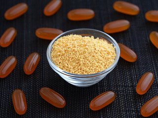 Soy lecithin in a glass bowl with soy lecithin softgels around it