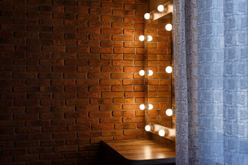 dressing table with mirror and lamps in the bedroom on the brown brick wall background with copy space for text. detail of the interior of a women's room in the style of loft and minimalism