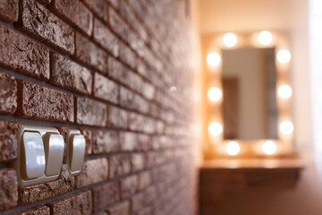 dressing table with mirror and lamps in the bedroom on the brown brick wall with light  switch background with copy space . detail of the interior of women's room in the style of loft and minimalism