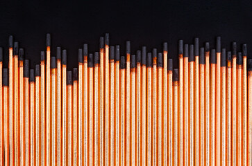 A background of round graphite gouging electrodes stacked vertically together. New copper straight rods.