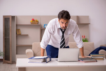 Obraz premium Young male employee working from home during pandemic