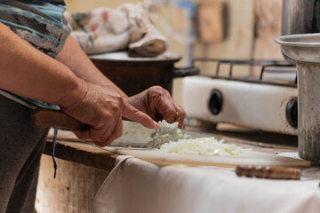 Old person cutting onions in a cutting board