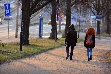 Para młodych ludzi spaceruje ścieżką wzdłuż drogi we Wrocławiu. - obrazy, fototapety, plakaty