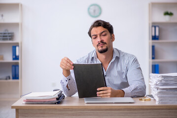 Young male employee unhappy with excessive work in the office