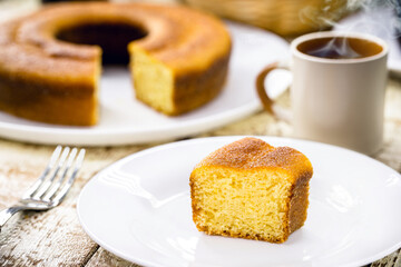 small slice of cornmeal cake, typical Brazilian rural cake made with corn flour, with hot coffee in the background, Brazilian breakfast