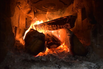 Burning fire in a brick oven under a cast iron slab
