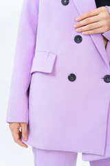 Close-up of a woman's light purple jacket with black buttons. Fashionable suit jacket and pants. Without a face.