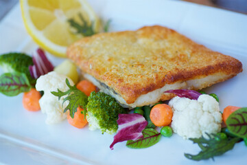Pollock fish, telapia or hake in breaded with vegetables. The concept of a menu for a restaurant or cafe.