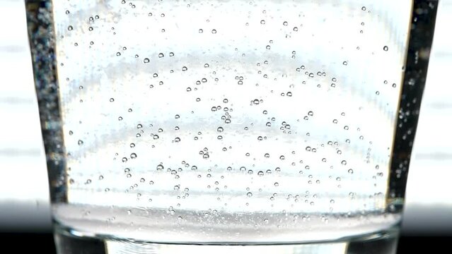Macro view of carbonation bubbles clinging to the inside of a glass, and slowly releasing and moving to the top.  Fizzy drink or antacid concept.