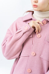 The sleeve of thick women warm pink coat with large buttons. A woman in turtleneck is buttoning her coat. White background.