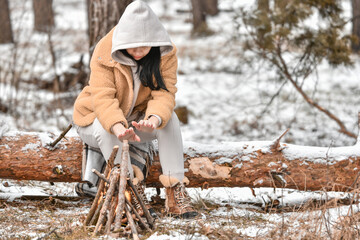  Girl makes a fire to warm herself in a snowy forest