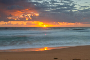 Naklejka na ściany i meble Sunrise at the seaside with waves and clouds