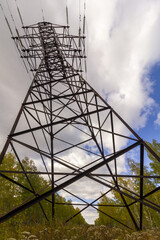 Electricity transmission pylon opposite the cloudy blue sky in summer. High power voltage electricity equipment.