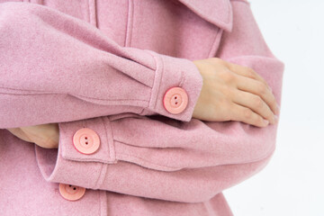 Hands folded together in woman warm pink coat with large buttons. Warm fashionable clothes. White background.