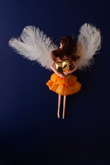 The angel with a sideways glance hugs golden heart in the beautiful dark blue night