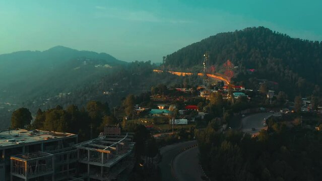 Aerial view of a village in green hills surrounded by trees in Murree, Pakistan