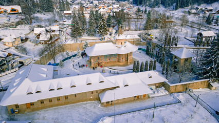 Aerial photography of Voronet Monastery, located in Suceava county, Romania in winter, sunny day with snow. Photo was shot from a drone with camera tilted down towards the building.