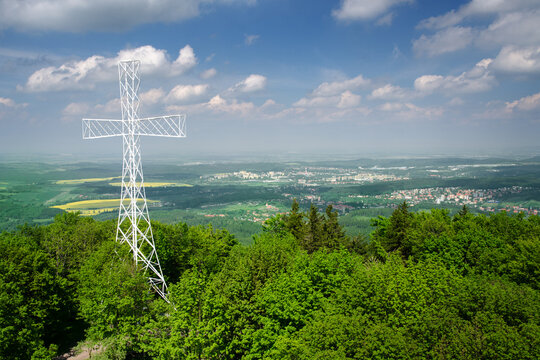 A large white cross atop Mount Chełmiec during a sunny summer day, with the city of Wałbrzych in the backgroud, Wałbrzyskie Mountains, Central Sudetes, Poland