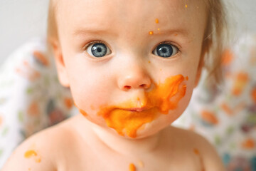 baby eats pumpkin puree at home, dirty baby close-up