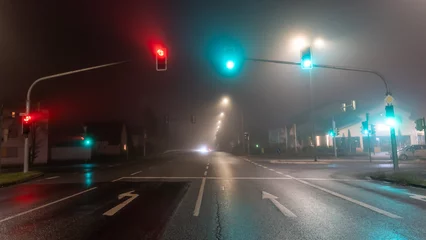 Wandaufkleber traffic lights on empty road in foggy night © Anselm