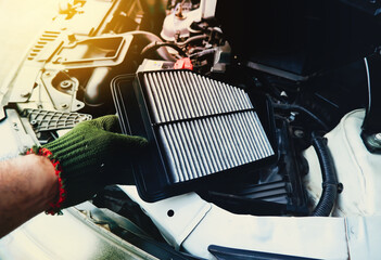 A mechanic is replacing an air filter in the engine car filter socket, automotive part concept