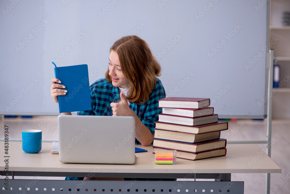 Wall mural young female student preparing for exams in the classroom