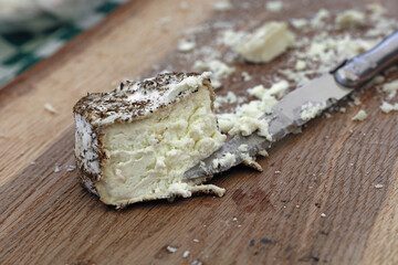 Fresh goat cheese with knife on wooden board