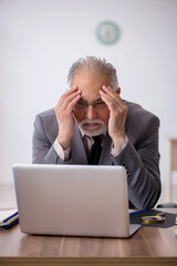 Old male employee working in the office