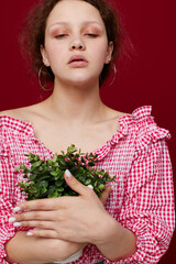 Young woman in pink blouse is posing with a plant in white pot close-up