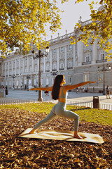 Young woman yoga outdoors at sunset in front of royal palace of Madrid