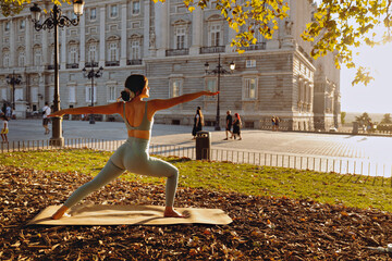 Young woman yoga outdoors at sunset in front of royal palace of Madrid
