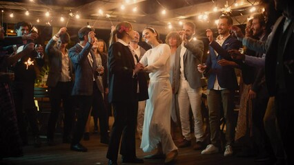 Beautiful Happy Lesbian Couple Celebrate Wedding at an Evening Reception Party with Diverse Multiethnic Friends. Queer Newlyweds Dancing and Kissing at a Restaurant Venue. LGBTQ Relationship Goals.