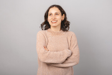 Portrait of a dreaming girl. Crossed arms portrait over gray background.