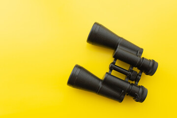 Binoculars on a light yellow background. Banner. Flat lay, top view.