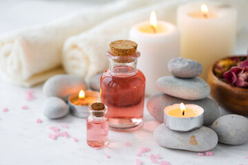 Concept of spa treatment in salon. Natural organic oil, towel, candles as decor. Atmosphere of relax, serenity and pleasure. Anti-stress and detox procedure. Luxury lifestyle. White wooden background