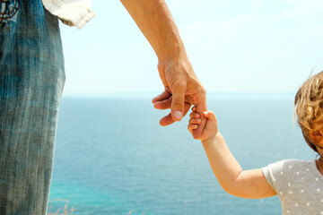 Fototapeta na wymiar hand of parent and child near the sea