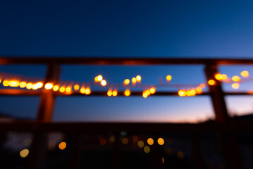 Out of focus christmas lights on the railings of a balcony at night.