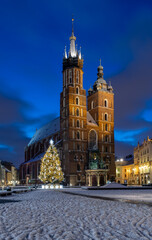 Fototapeta na wymiar St Mary's church on snow covered Main Square in winter Krakow, illuminated in the night.