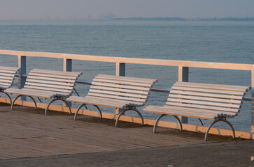 Baltic sea coast, morning view of white benches on pier at Gdynia Orlowa sea resort, Poland.