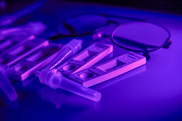 5 covid-19 antigen self-tests positive, buffer bottles and thin black-rimmed glasses on a light...