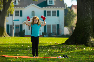 Fitness child. Sport exercise for kids. Sporty children, healthy Lifestyle. Child boy lifting dumbbells outside.