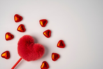 Fluffy red heart and lots of shiny candy in the shape of hearts wrapped in foil
